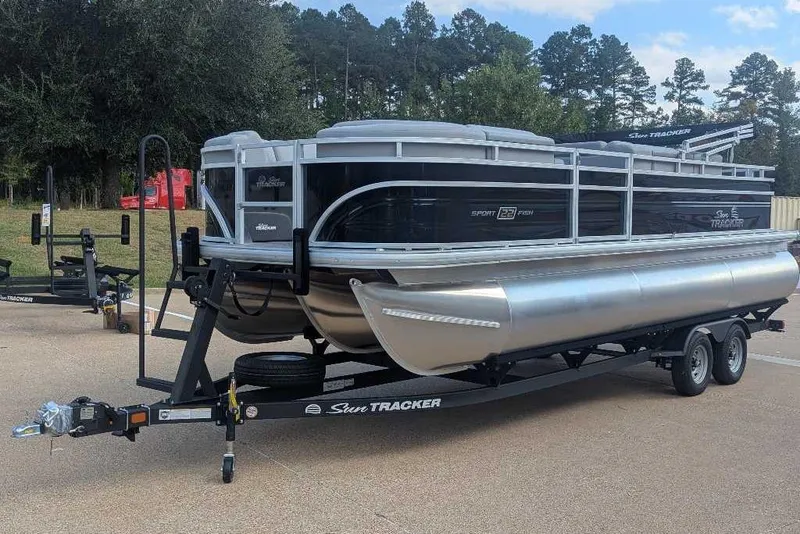 Slide: The Image of 2026 Sun Tracker SportFish 22 XP3 pontoon boat on trailer, parked outdoors. - 9