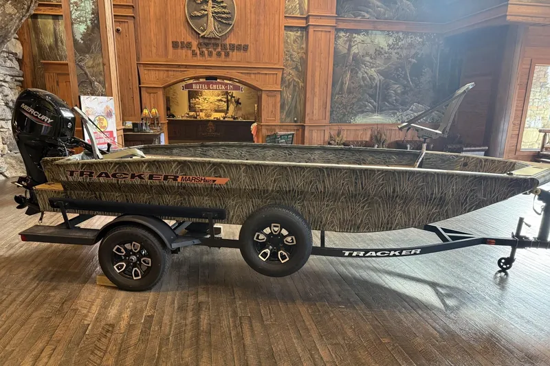 The Image of 2026 Tracker Grizzly 1756 T Marsh boat on display indoors, featuring camouflage design. - 0