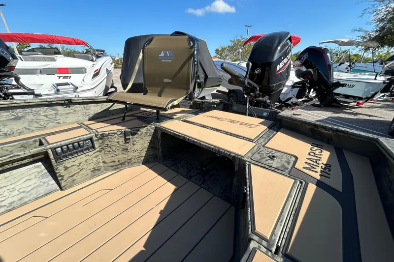 Slide: The Image of 2026 Tracker Grizzly 1756 T Marsh boat interior with seating and motor, displayed outdoors. - 3