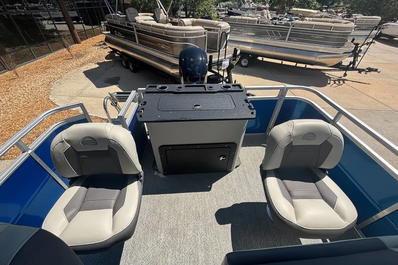 Slide: The Image of 2026 Sun Tracker Fishin' Barge 20 DLX interior with seating and console, parked outdoors. - 14
