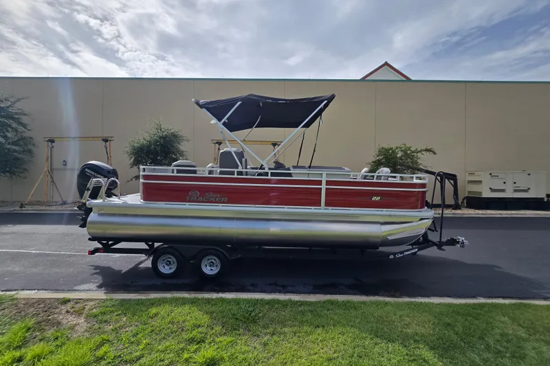 Slide: The Image of 2026 Sun Tracker Fishin' Barge 22 DLX pontoon boat on trailer, parked outdoors. - 67