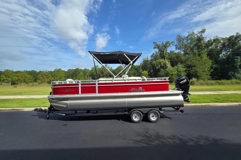 Slide: The Image of 2026 Sun Tracker Fishin' Barge 22 DLX pontoon boat on trailer, parked outdoors. - 68