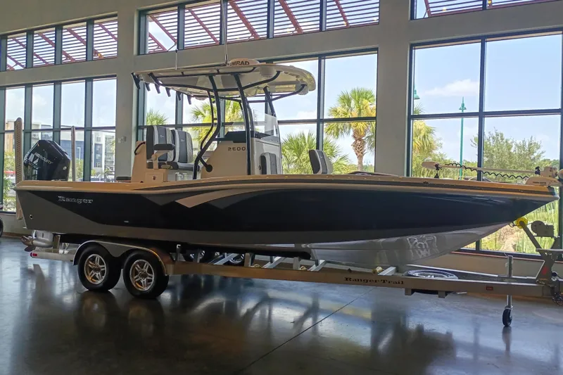 Slide: The Image of 2026 Ranger 2600 Bay boat displayed indoors on a trailer. - 2
