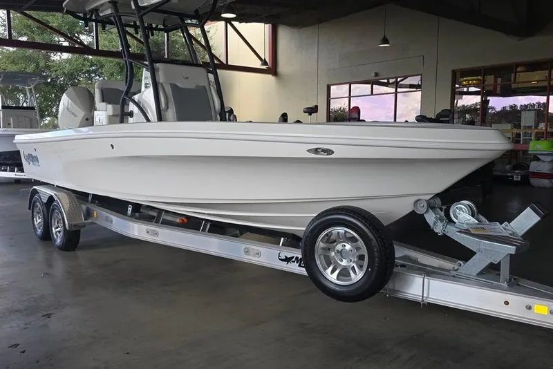 The Image of 2026 Mako 24 APEX boat on trailer in showroom setting. - 0