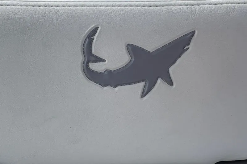 Slide: The Image of Gray shark logo on white leather seat of 2026 Mako 24 APEX boat. - 14