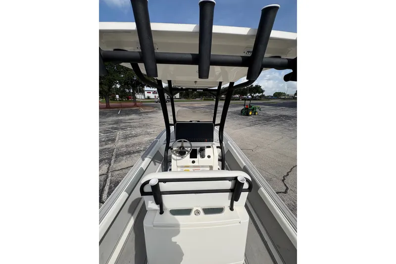 Slide: The Image of 2026 Mako 24 APEX boat interior with steering console and T-top in a parking lot. - 8