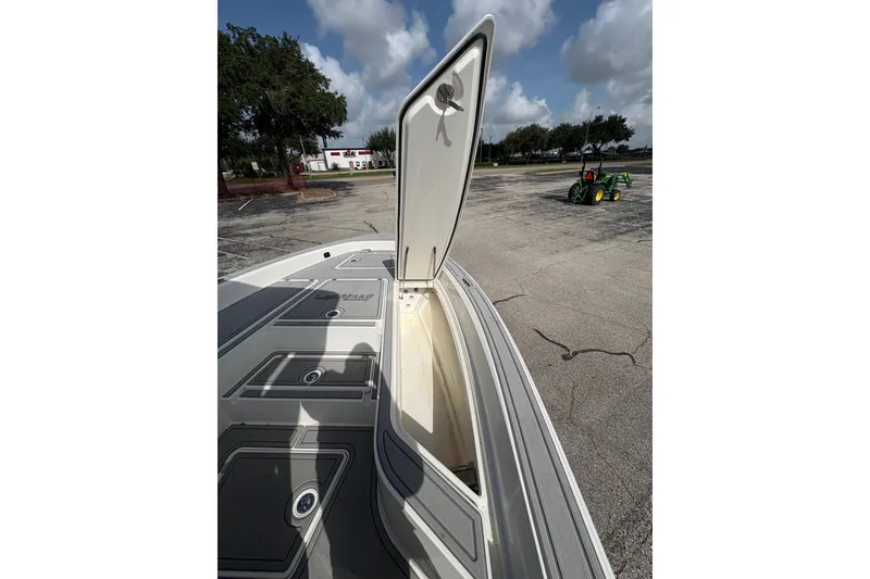 Slide: The Image of Open storage compartment on 2026 Mako 24 APEX boat, parked outdoors under cloudy sky. - 11