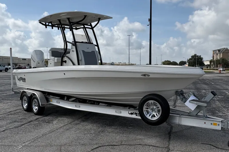 Slide: The Image of 2026 Mako 24 APEX boat on trailer under cloudy sky in parking lot. - 6