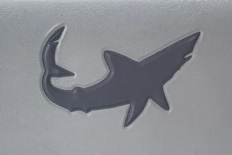 Slide: The Image of Gray shark logo on white leather seat of 2026 Mako 24 APEX boat. - 15