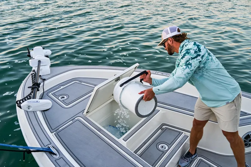 Slide: The Image of Man pouring water on 2026 Mako 24 APEX boat deck, near water. - 91