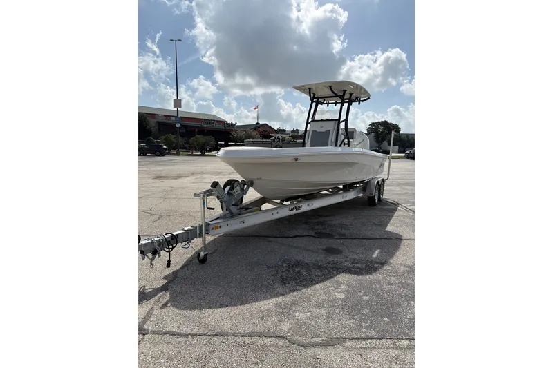 Slide: The Image of 2026 Mako 24 APEX boat on trailer in parking lot under cloudy sky. - 2