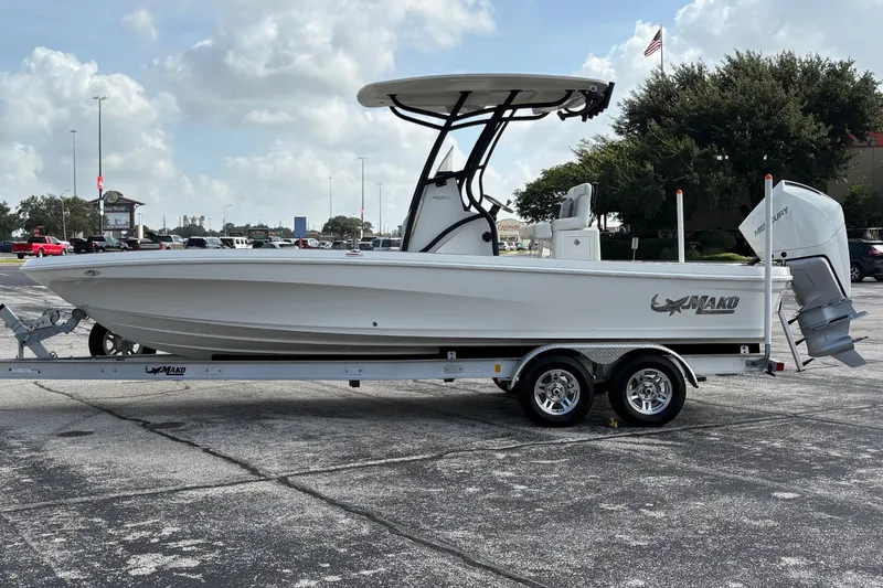 Slide: The Image of 2026 Mako 24 APEX boat on trailer in parking lot under cloudy sky. - 2