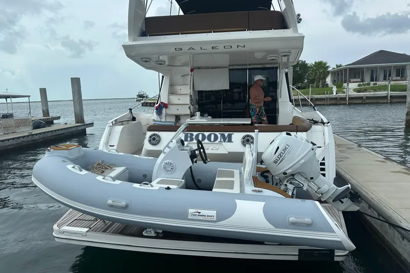 Slide: The Image of A 2026 East Marine 360 inflatable boat with Suzuki motor docked near a yacht. - 14