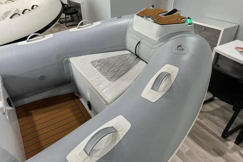Slide: The Image of Inflatable boat interior, East Marine 360 model, 2026, featuring gray seating and wooden flooring. - 8