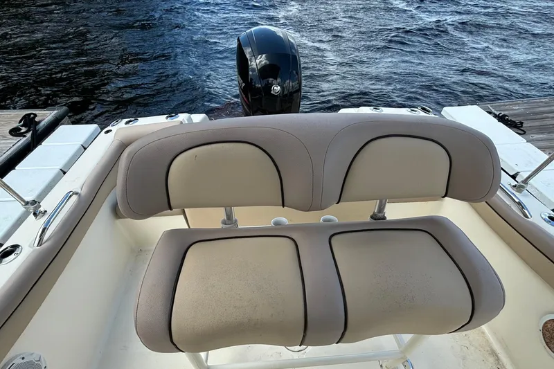 Slide: The Image of 2015 Scout 215 XSF boat with cushioned seating and outboard motor by the water. - 10