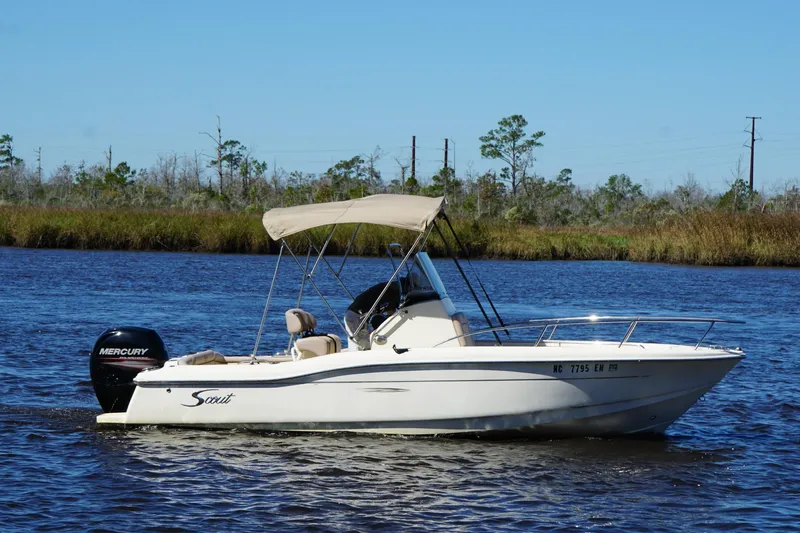 Slide: The Image of 2015 Scout 215 XSF boat cruising on a calm river with scenic background. - 18