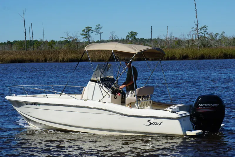 Slide: The Image of 2015 Scout 215 XSF boat cruising on a calm river with a Mercury outboard motor. - 19