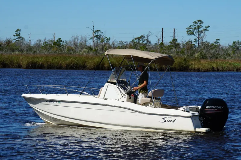 Slide: The Image of 2015 Scout 215 XSF boat cruising on a calm river with a Mercury engine. - 2
