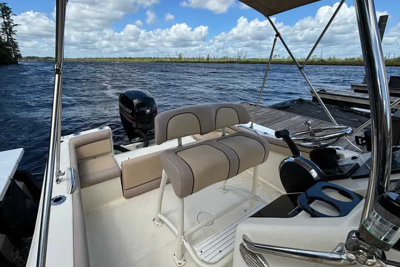 Slide: The Image of 2015 Scout 215 XSF boat interior with seating and steering, docked by a scenic lake. - 6