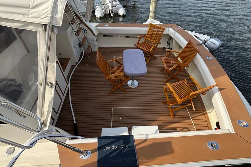 Slide: The Image of 1986 Viking 48 Convertible yacht deck with wooden chairs and table, docked by the water. - 11