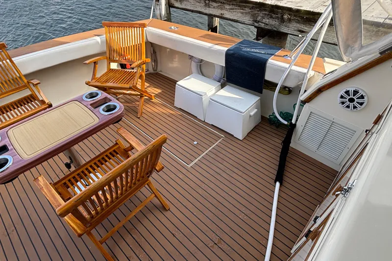 Slide: The Image of 1986 Viking 48 Convertible yacht deck with wooden chairs and table, docked by water. - 13
