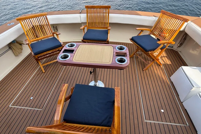 Slide: The Image of Deck of 1986 Viking 48 Convertible yacht with wooden chairs and table, overlooking water. - 14