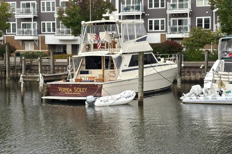 Slide: The Image of 1986 Viking 48 Convertible yacht docked in marina, surrounded by modern waterfront buildings. - 3