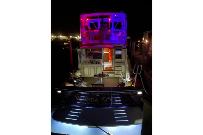 Slide: The Image of 1986 Viking 48 Convertible yacht illuminated with vibrant blue and red lights at night. - 5