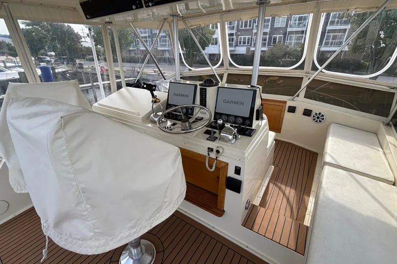 Slide: The Image of 1986 Viking 48 Convertible yacht cockpit with Garmin navigation, white seating, and wood flooring. - 51