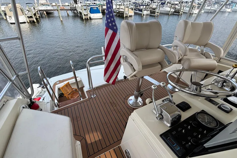 Slide: The Image of 1986 Viking 48 Convertible yacht helm with chairs, American flag, and marina view. - 57