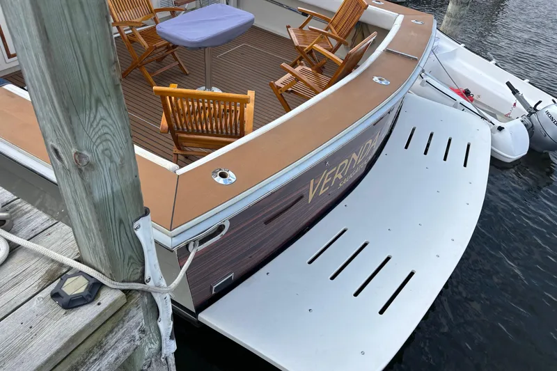 Slide: The Image of 1986 Viking 48 Convertible yacht with wooden deck and chairs, docked by the water. - 60