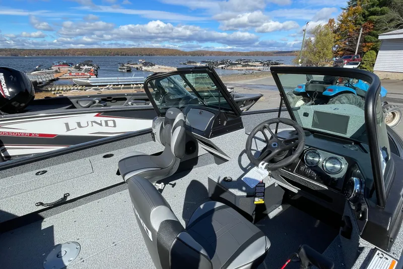Slide: The Image of 2026 Lund 1775 Adventure Sport boat interior with steering wheel, seats, and lake view. - 9