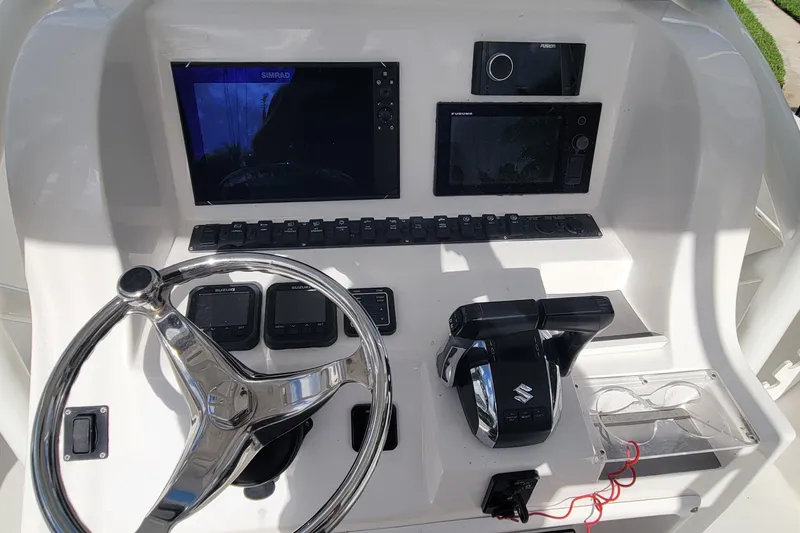 Slide: The Image of 2022 Twin Vee 260 CC SE Classic boat dashboard with steering wheel and electronic controls. - 2