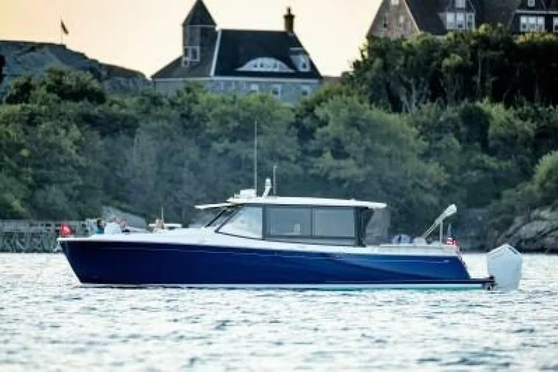 The Image of 2025 MJM 4 boat cruising on turquoise waters near a coastal city. - 2