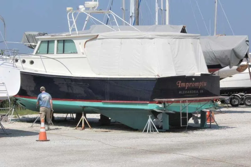 Slide: The Image of 2005 Mast & Mallet Thomas Point boat on land, covered, with a person nearby. - 2