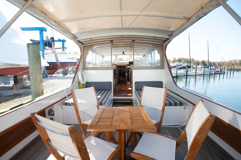 Slide: The Image of 2005 Mast & Mallet Thomas Point boat interior with wooden table and chairs, docked at marina. - 4