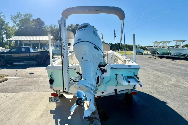 Slide: The Image of 2023 Key West 188 Bay Reef boat with outboard motor, parked outdoors on a sunny day. - 2