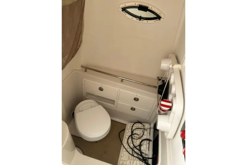 Slide: The Image of 2015 Sailfish 290 CC boat interior with open door revealing compact restroom. - 15