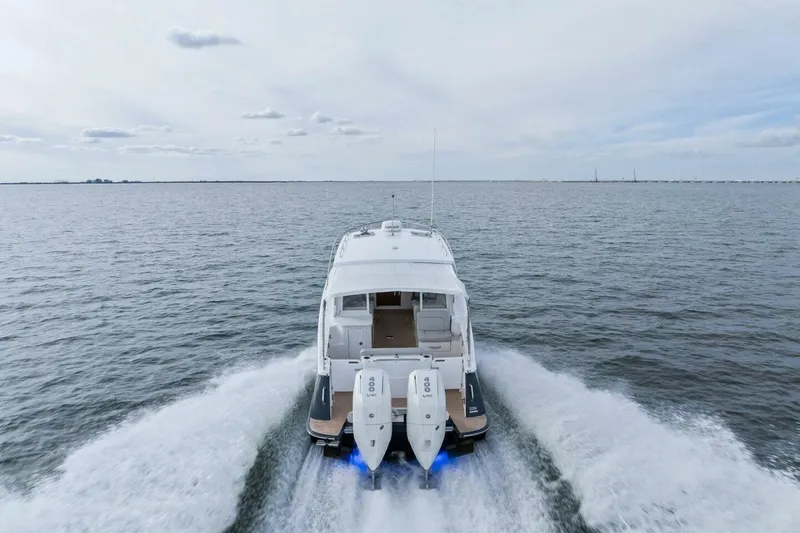 Slide: The Image of 2025 MJM 35 boat cruising on open water, rear view with twin engines. - 53