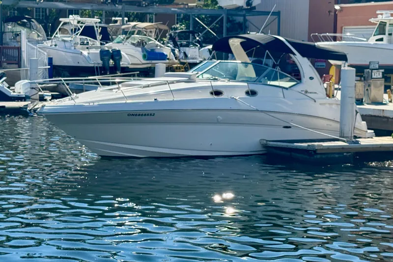 Slide: The Image of 2003 Sea Ray 320 Sundancer docked at a marina, surrounded by water and other boats. - 10
