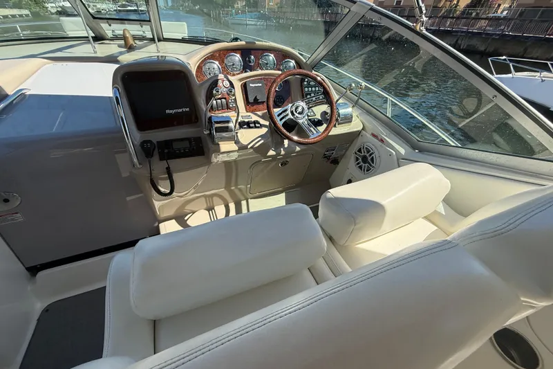 Slide: The Image of 2003 Sea Ray 320 Sundancer cockpit with steering wheel and control panel, docked by water. - 14