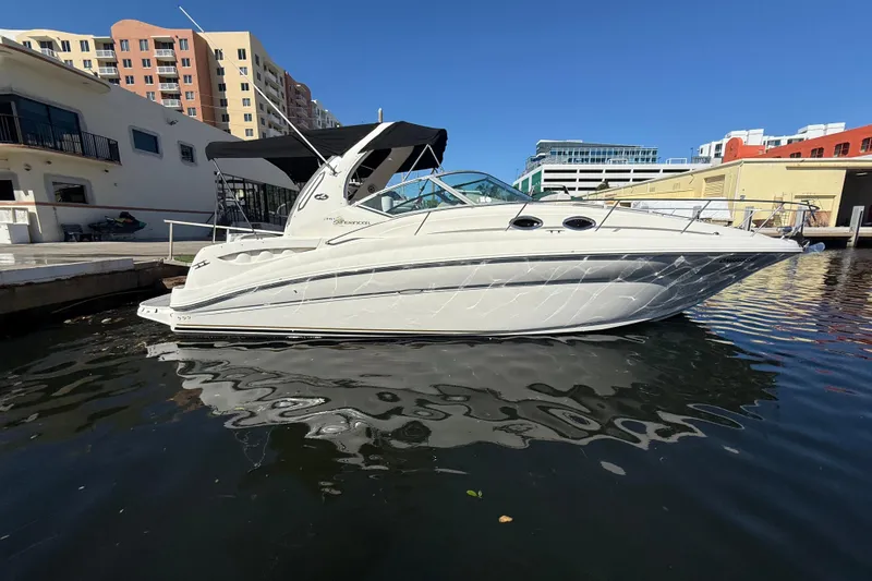 Slide: The Image of 2003 Sea Ray 320 Sundancer yacht docked in a marina, under clear blue skies. - 2