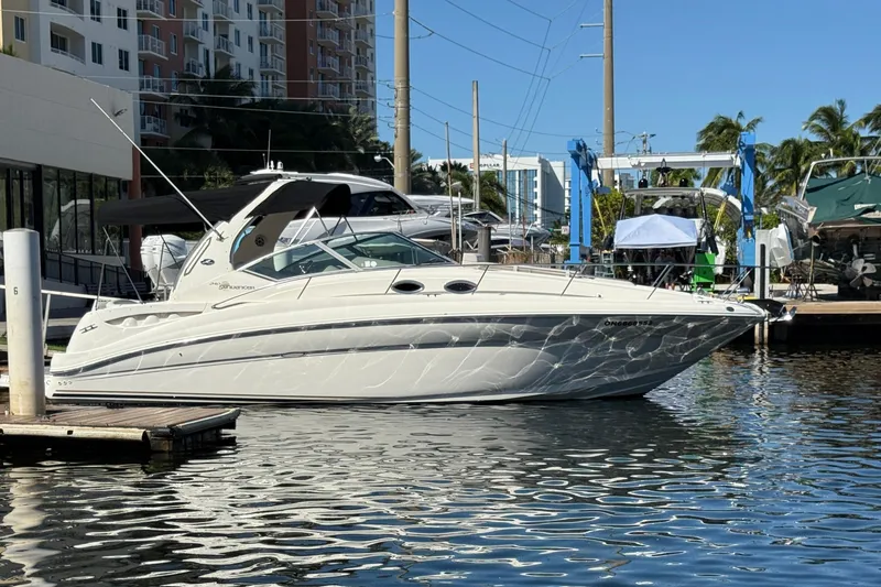 Slide: The Image of 2003 Sea Ray 320 Sundancer yacht docked at marina, surrounded by buildings and palm trees. - 3