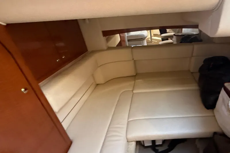 Slide: The Image of 2003 Sea Ray 320 Sundancer cabin interior with beige seating and wooden cabinetry. - 30