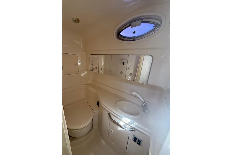 Slide: The Image of 2003 Sea Ray 320 Sundancer bathroom with sink, toilet, and porthole window. - 31