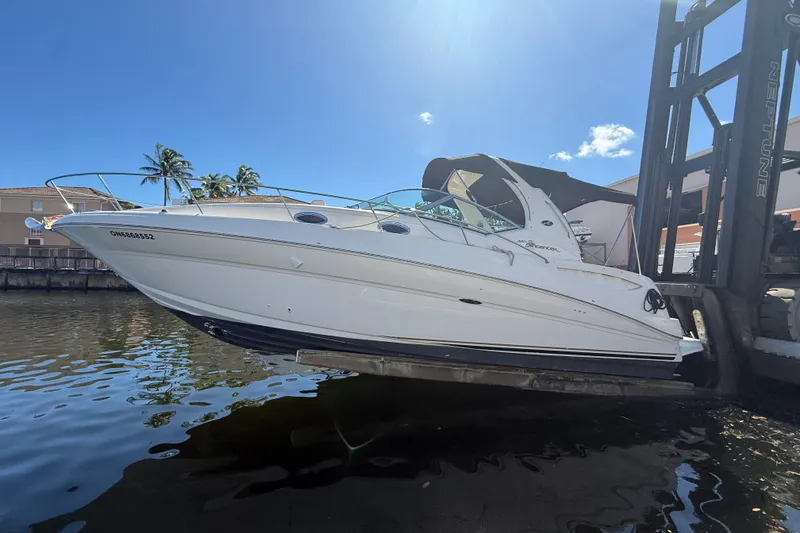 Slide: The Image of 2003 Sea Ray 320 Sundancer boat on lift, sunny day, palm trees in background. - 7
