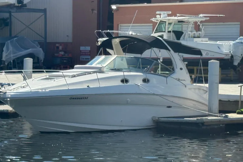 Slide: The Image of 2003 Sea Ray 320 Sundancer docked at marina, featuring sleek design and black canopy. - 9