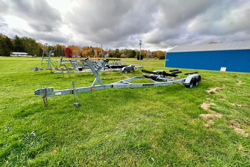 Slide: The Image of Boat trailers on grassy field near blue building, overcast sky. Chris-Craft Corsair 25, 2003. - 14