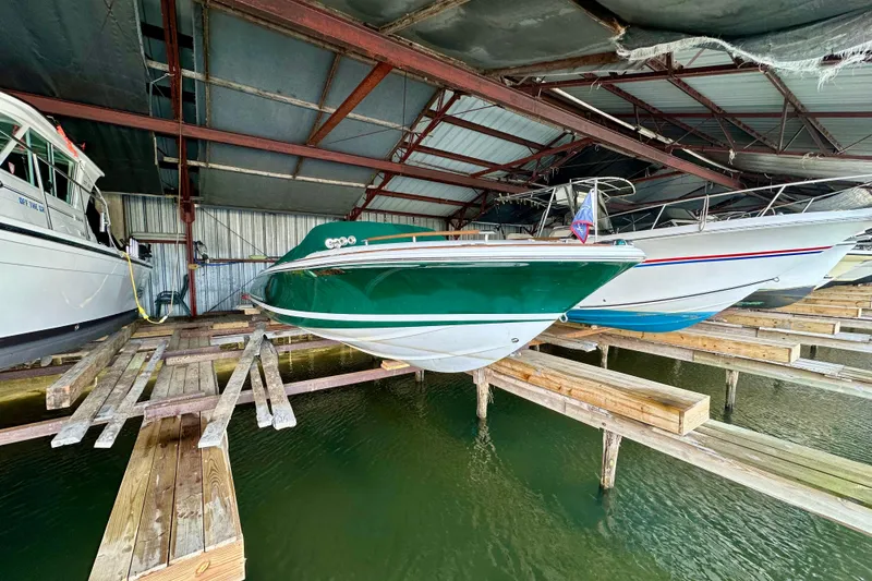 Slide: The Image of 2003 Chris-Craft Corsair 25 boat in covered dock, green hull, wooden supports. - 2