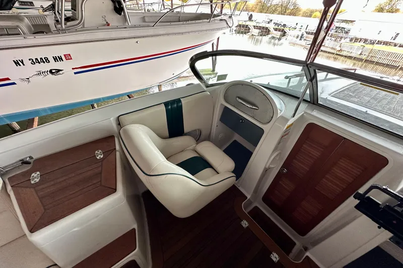 Slide: The Image of 2003 Chris-Craft Corsair 25 cockpit with white and teal seating, wooden accents, and steering wheel. - 9